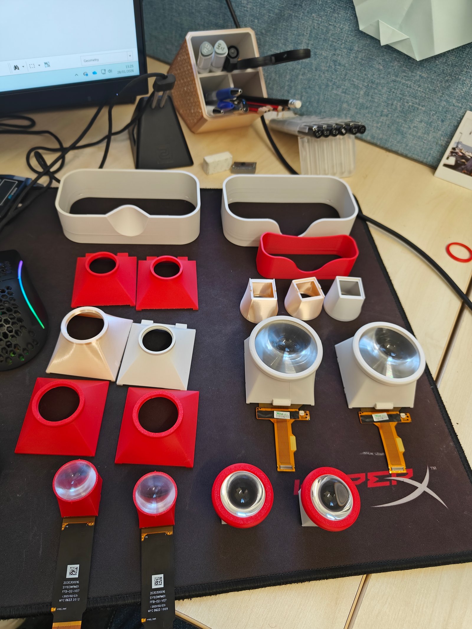 Optical bench test: display modules, lenses and printed lens cones laid out for evaluation